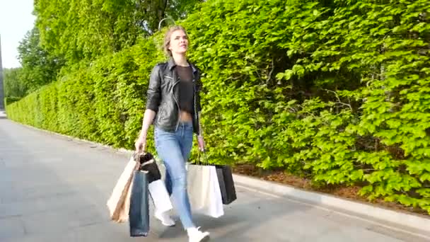 Wandelen meisje met nieuwe cadeaus in de stad. Slow motion — Stockvideo