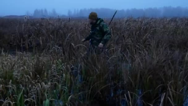 Cacciatore di anatre con fucile alla ricerca di uccelli sparati attraverso l'erba thich acqua — Video Stock