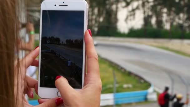 Zeitlupe Nahaufnahme von Mädchenhänden, die ihr Handy in der Hand halten und Video vom MotoGP-Wettbewerb drehen. — Stockvideo