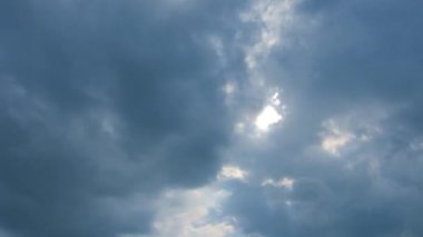 Mavi gökyüzünde güneş ışığıyla hareket eden bulutlar