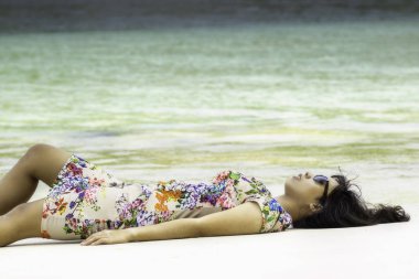 Genç çekici Endonezya kız deniz arka plan ile kumlu bir plaj üzerinde yalan