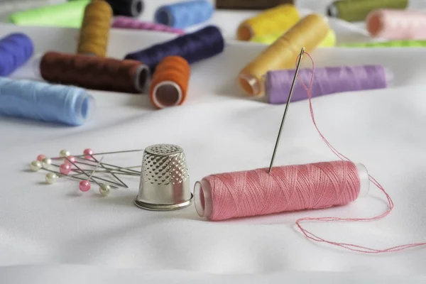 Needle, pins, thimble and colorful spools of thread — Stock Photo, Image