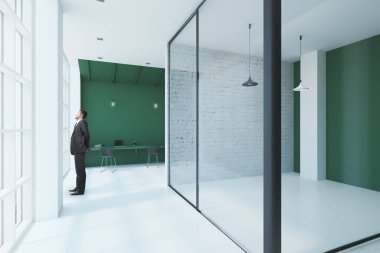 yeşil duvar ve boş konferans salonu ile modern ofis pencere bakarak işadamı. 