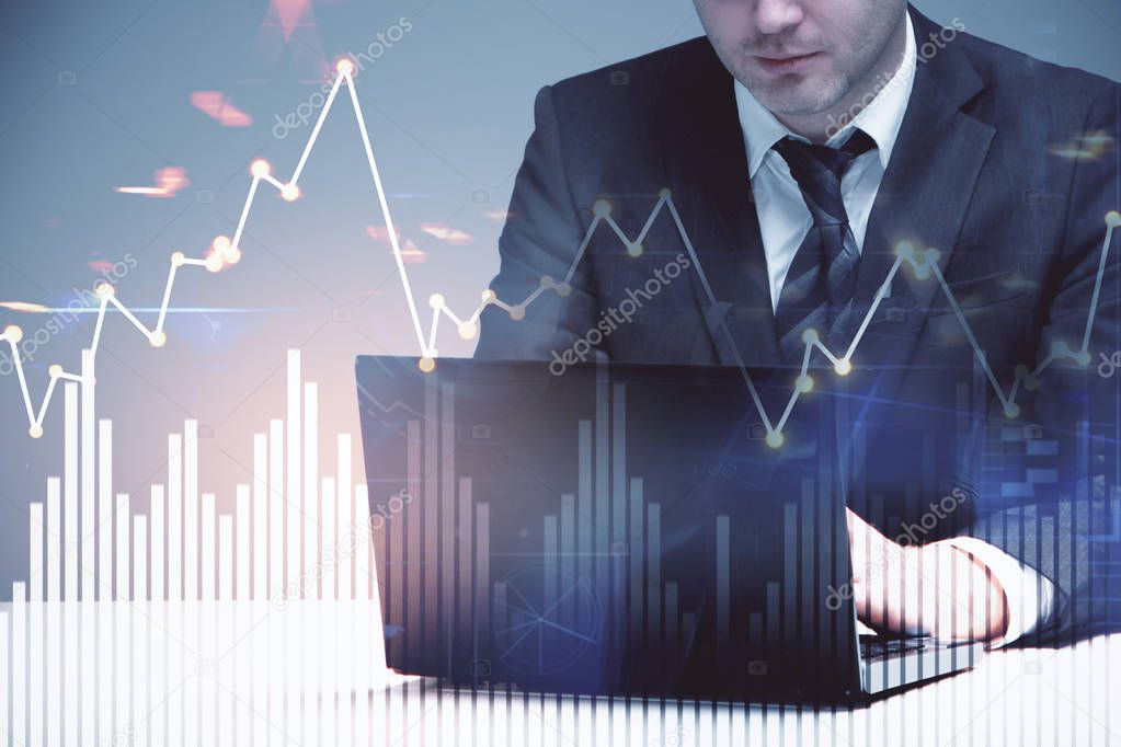 double exposure of businessman working with laptop in office and business chart with financial graphs
