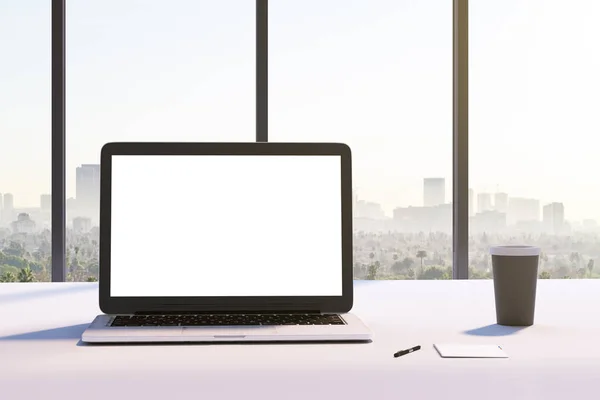 前视图的样机白色笔记本电脑屏幕上的现代办公桌上的城市景观背景 — 图库照片