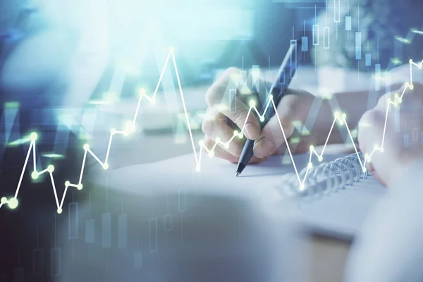 Financial forex graph displayed on hands taking notes background. Concept of research. Multi exposure