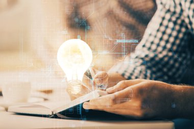 Ampul lambası fikir simgesinin gelecek arayüzü ve yazma adamı el altyapısı üzerindeki görüntüsü. Çift pozlama.