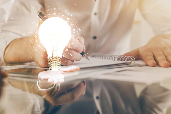 Vista del icono del concepto de la idea de la lámpara de bombilla en una interfaz futurista con el fondo de la mano del hombre de escritura. Doble exposición. — Foto de Stock