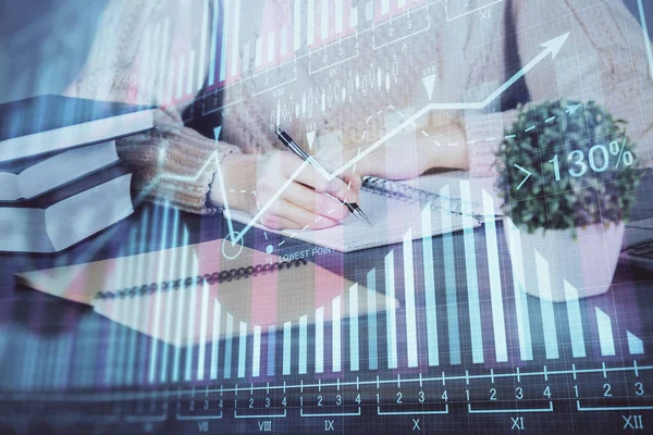 Forex graph on hand taking notes background. Concept of research. Double exposure