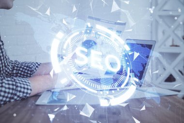 Arka planda bilgisayarla çalışan bir adamla iki kez simgeye maruz kalıyoruz. Arama motoru optimizasyonu kavramı.