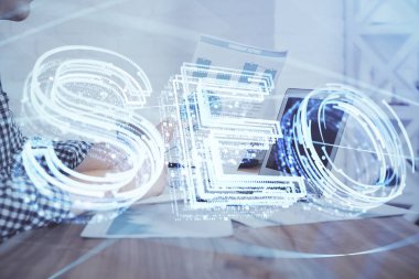Arka planda bilgisayarla çalışan bir adamla iki kez simgeye maruz kalıyoruz. Arama motoru optimizasyonu kavramı.