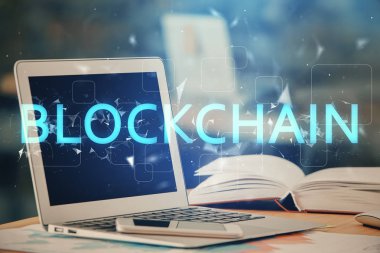 Engelleme zinciri ve kripto ekonomi temalı hologram ve bilgisayar geçmişi olan bir masa. Bitcoin kripto para kavramı.