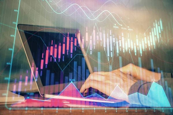 Double exposure of businessmans hands with laptop and stock market graph background. Concept of research and trading.