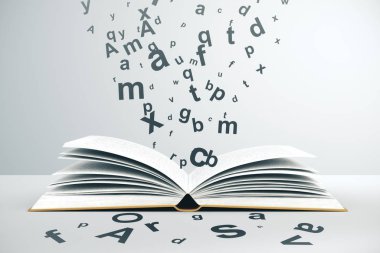 Açık kitap ve uçan harfler