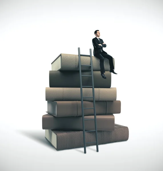 Homme en costume assis sur une pile de livres — Photo