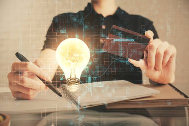 Elinde bir kredi kartı ve ampul çizimi olan bir adamın ellerine iki kez maruz kalmış. Fikir E-ticaret kavramı.