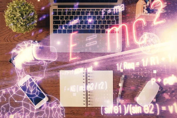 Physics and math theme hologram with formula drawings over computer on the desktop background. Top view. Multi exposure. Concept of education.