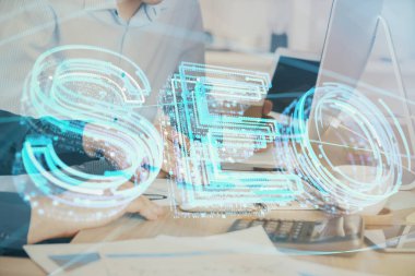Arka planda bilgisayar üzerinde çalışan bir adamla birlikte çok sayıda simgeye maruz kalma. Arama motoru optimizasyonu kavramı.