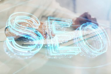 Arka planda bilgisayar üzerinde çalışan bir adamla birlikte çok sayıda simgeye maruz kalma. Arama motoru optimizasyonu kavramı.