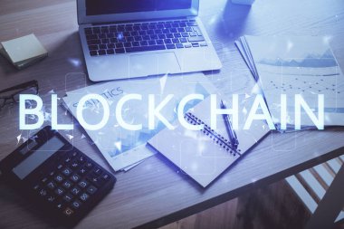Engelleme zinciri ve kripto ekonomi temalı hologram ve bilgisayar geçmişi olan bir masa. Bitcoin kripto para kavramı.
