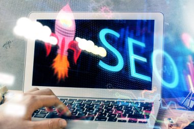 Arka planda bilgisayar üzerinde çalışan bir adamla birlikte çok sayıda simgeye maruz kalma. Arama motoru optimizasyonu kavramı.