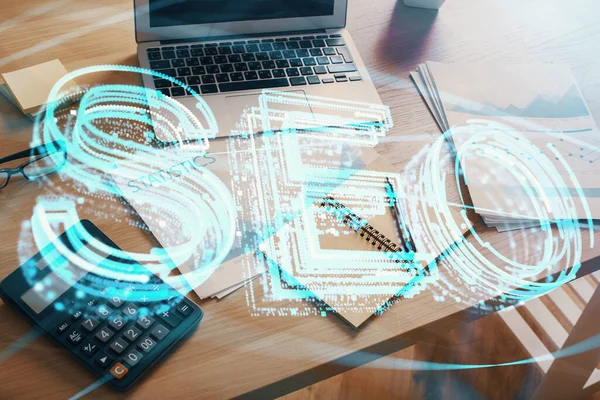 Dubbele belichting van tafel met computer en seo tekening hologram. Zoekoptimalisatie concept. — Stockfoto