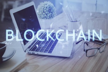 Engelleme zinciri ve kripto ekonomi temalı hologram ve bilgisayar geçmişi olan bir masa. Bitcoin kripto para kavramı.