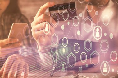 Bir kredi kartı ve sosyal ağ temalı hologram çizimi tutan bir kadın ve erkeğin online alışverişine iki kez maruz kalıyorlar. Bağlayan ve E-ticaret yapan insanlar çevrimiçi konsept üzerinden ödeme yapıyorlar.