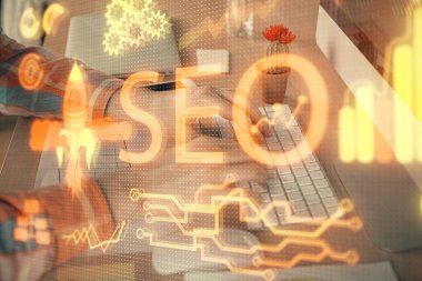 Arka planda bilgisayarla çalışan bir adamla iki kez simgeye maruz kalıyoruz. Arama motoru optimizasyonu kavramı.