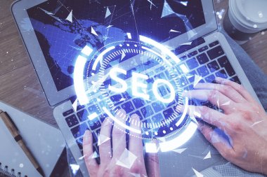 Bilgisayar klavyesinin ve SEO hologram çiziminin üzerine yazı yazan bir adamın eline çok kez maruz kalmış. Üst Manzara. Arama optimizasyon kavramı.