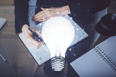 El üstünde tutulan ampul hologramı notlar alıyor. Fikir kavramı. Çift pozlama