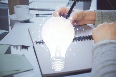 El üstünde tutulan ampul hologramı notlar alıyor. Fikir kavramı. Çift pozlama