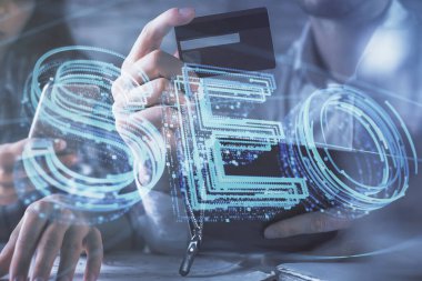 Bir kredi kartı ve SEO hologramı çizimi tutan kadın ve erkeğin online alışverişine iki kez maruz kalıyorlar. arama optimizasyonu E-ticaret ödeme çevrimiçi konsept.