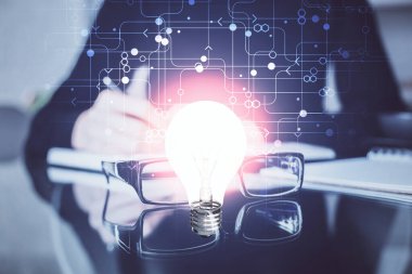 El üstünde tutulan ampul hologramı notlar alıyor. Fikir kavramı. Çift pozlama