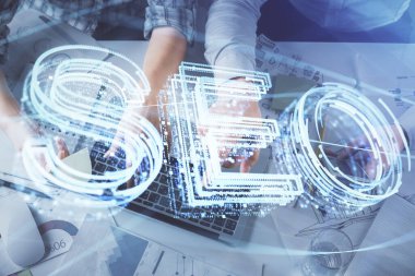 SEO hologram çizimleri ve birlikte çalışan kadın ve erkeğin çifte pozu. Arama motoru konsepti. Bilgisayar arkaplanı. Üst Görünüm.