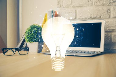 Bilgisayar ofisinde ampul simgesi hologramıyla birlikte. Çifte maruziyet. Fikir kavramı.