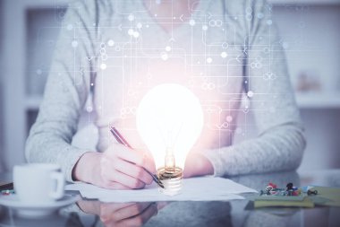 El üstünde tutulan ampul hologramı notlar alıyor. Fikir kavramı. Çift pozlama