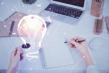 El üstünde tutulan ampul hologramı notlar alıyor. Fikir kavramı. Çift pozlama