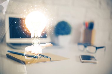 Bilgisayar ofisinde ampul simgesi hologramıyla birlikte. Çifte maruziyet. Fikir kavramı.