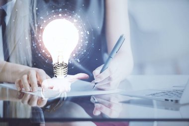 El üstünde tutulan ampul hologramı notlar alıyor. Fikir kavramı. Çift pozlama