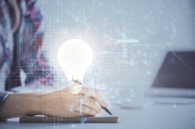 El üstünde tutulan ampul hologramı notlar alıyor. Fikir kavramı. Çift pozlama