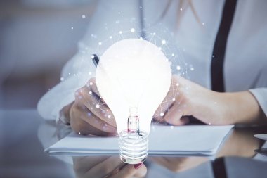 El üstünde tutulan ampul hologramı notlar alıyor. Fikir kavramı. Çift pozlama