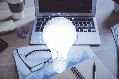 Bilgisayar ofisinde ampul simgesi hologramıyla birlikte. Çifte maruziyet. Fikir kavramı.