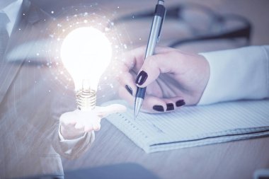 El üstünde tutulan ampul hologramı notlar alıyor. Fikir kavramı. Çift pozlama