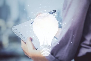 El üstünde tutulan ampul hologramı notlar alıyor. Fikir kavramı. Çift pozlama