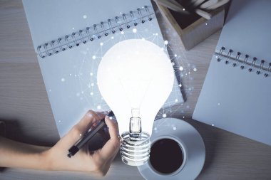 El üstünde tutulan ampul hologramı notlar alıyor. Fikir kavramı. Çift pozlama