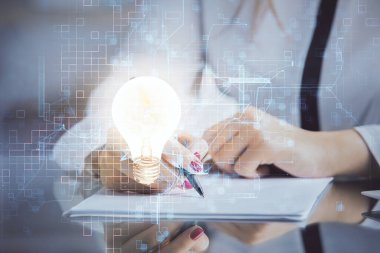 El üstünde tutulan ampul hologramı notlar alıyor. Fikir kavramı. Çift pozlama