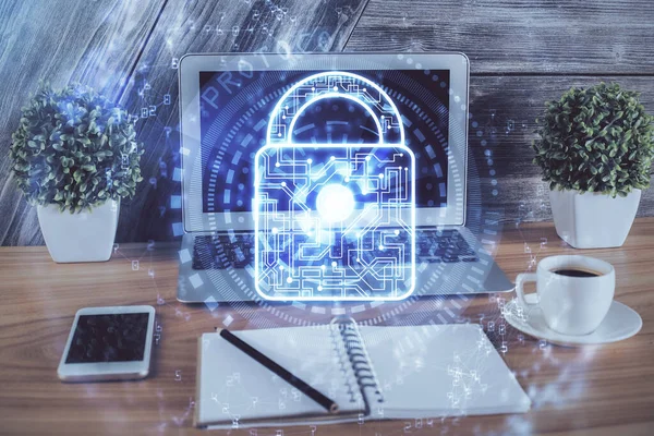 Double exposure of desktop with computer and lock icon hologram. Concept of data safety.