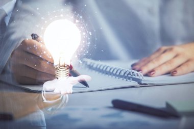 El üstünde tutulan ampul hologramı notlar alıyor. Fikir kavramı. Çift pozlama