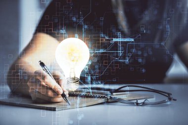 El üstünde tutulan ampul hologramı notlar alıyor. Fikir kavramı. Çift pozlama